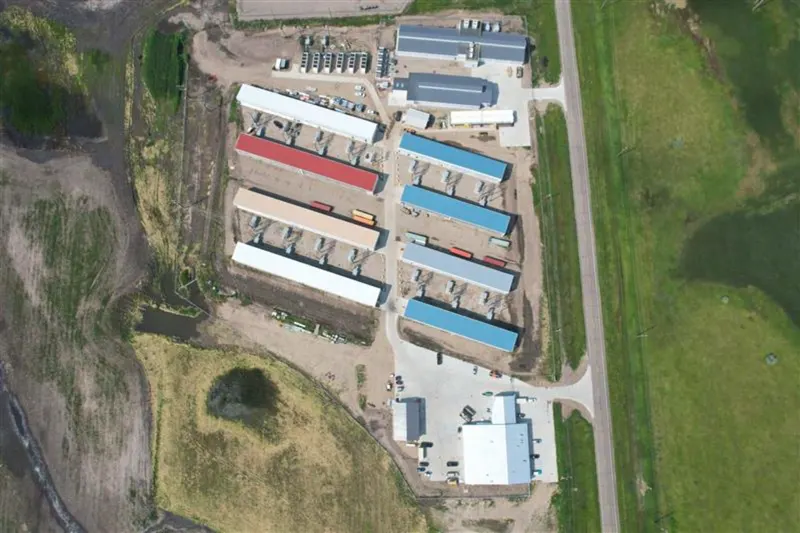 Aerial view of the Jamestown hosting campus: long metal-roofed buildings in two ranks on flat prairie, sidewall exhaust fans down the flanks, transformer yard at the edge of the site