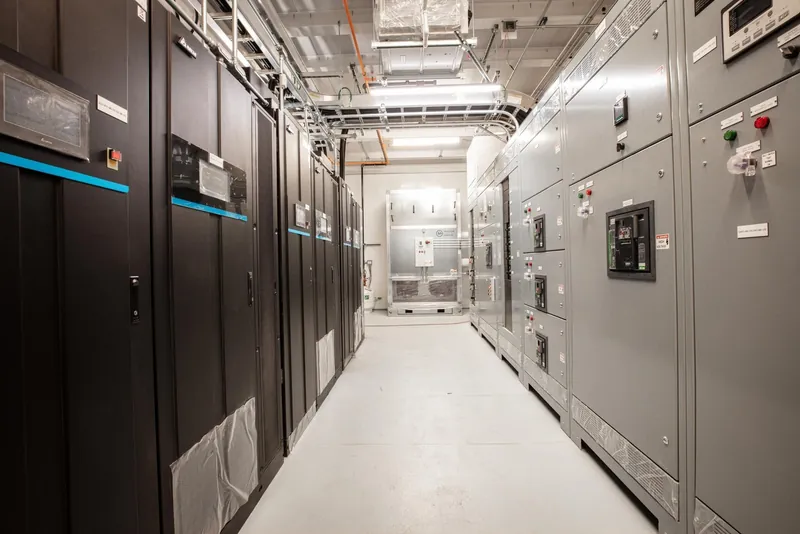 UPS cabinets and a switchgear lineup installed indoors, cable tray and conduit overhead